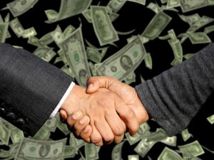 Two men shaking hands with money floating behind them